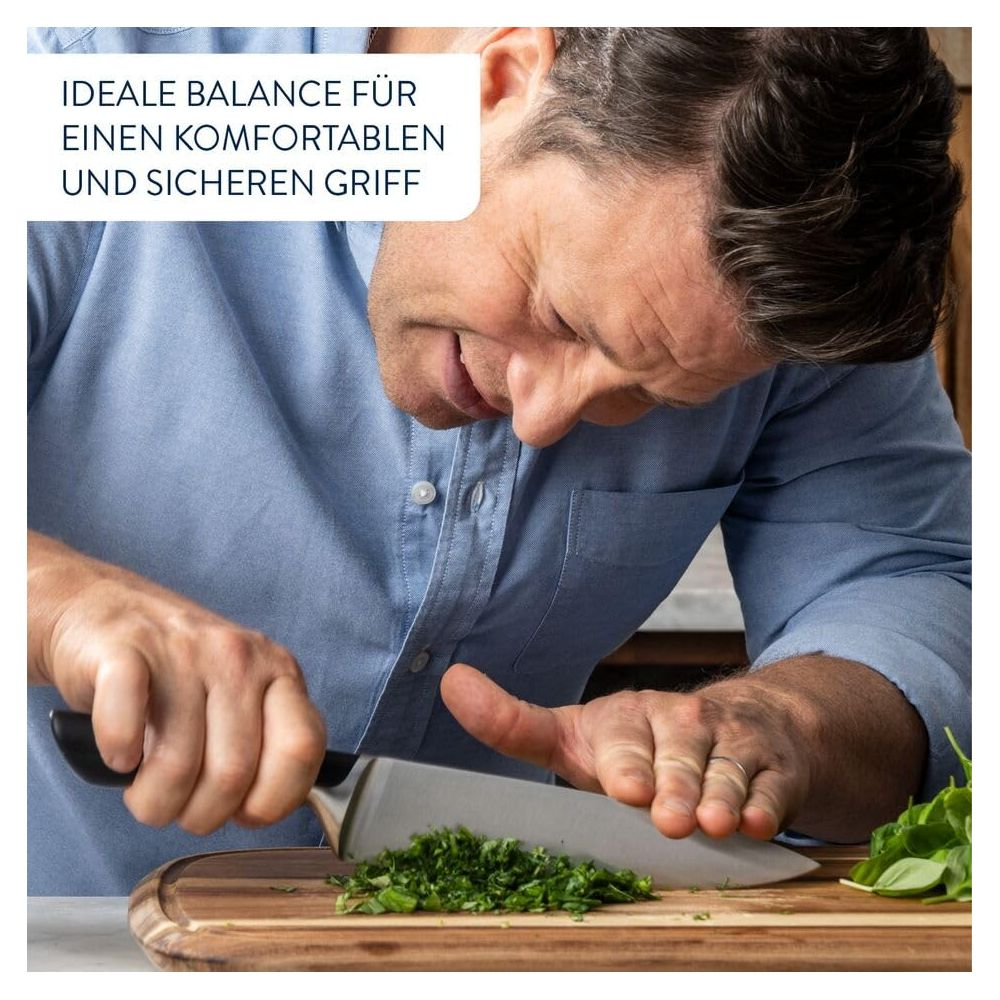Mann in blauem Hemd hackt Kräuter mit Messer auf Holzbrett.