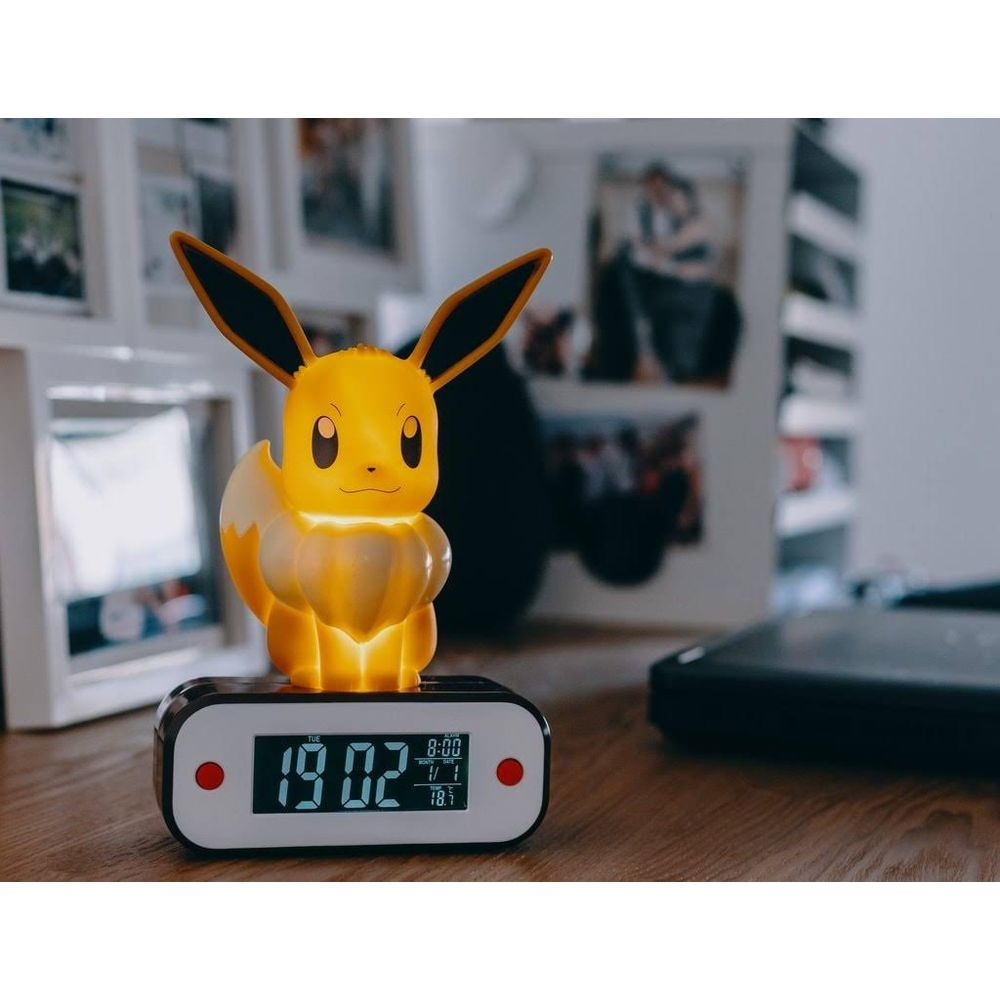 Świecący budzik Eevee na drewnianym stole. Pokazuje 19:02.