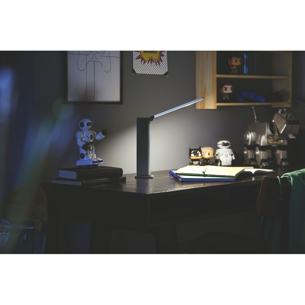 Ein Schreibtisch mit Lampe, Roboterfiguren, Büchern und Spielzeug.