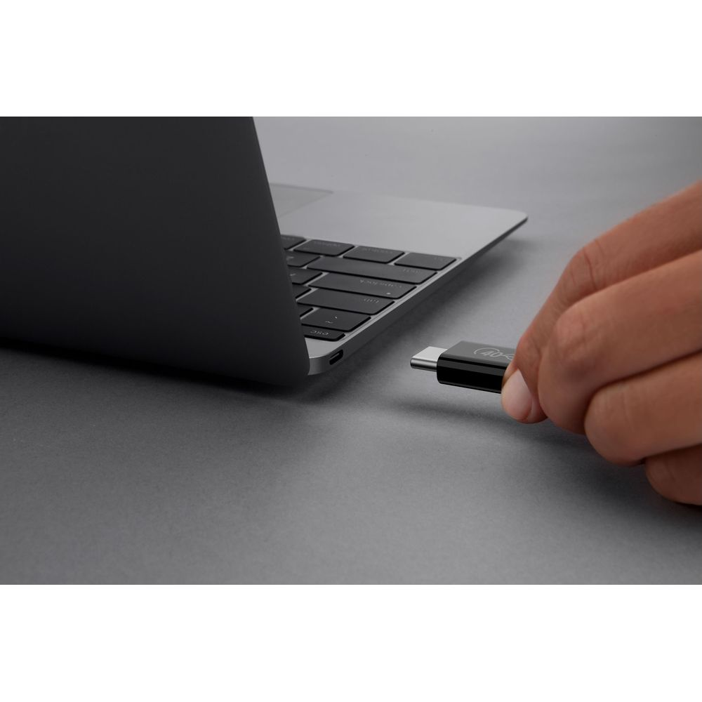 Een hand steekt een zwarte USB-C stick in een MacBook.
