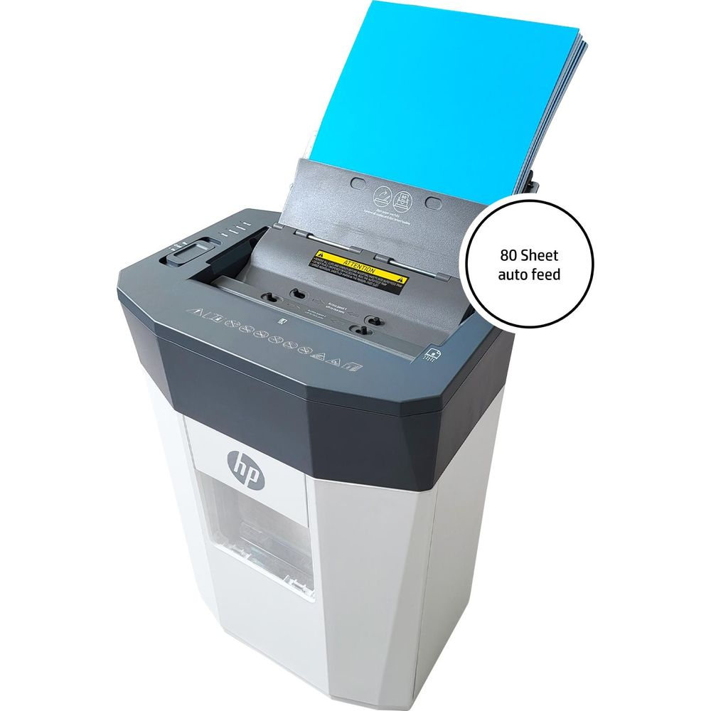 Un distruggidocumenti bianco e grigio con carta blu nel vassoio di alimentazione automatica.