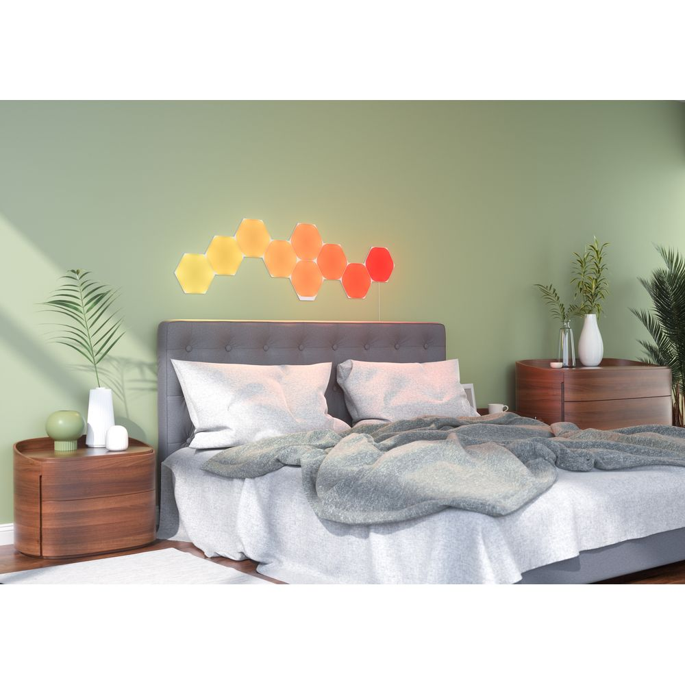 Ein Schlafzimmer mit einem Bett, Nachttischen und sechseckigen Lichtern an der Wand.