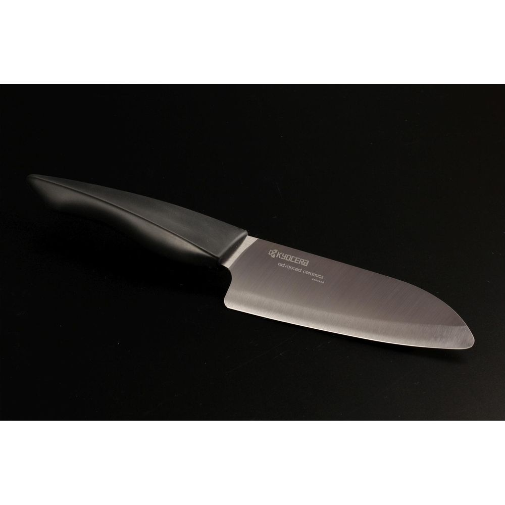 Un couteau céramique Kyocera à manche noir sur fond noir.