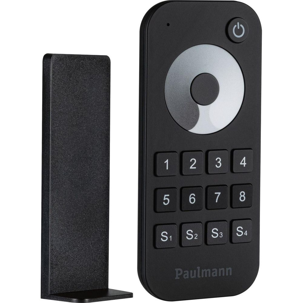 Czarny pilot z przyciskami i pierścieniem, obok uchwytu.