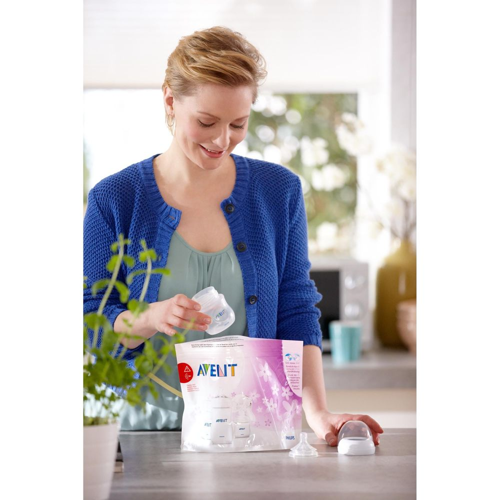 Eine Frau in einem blauen Cardigan hält eine Avent-Flasche über einer Avent-Verpackung.