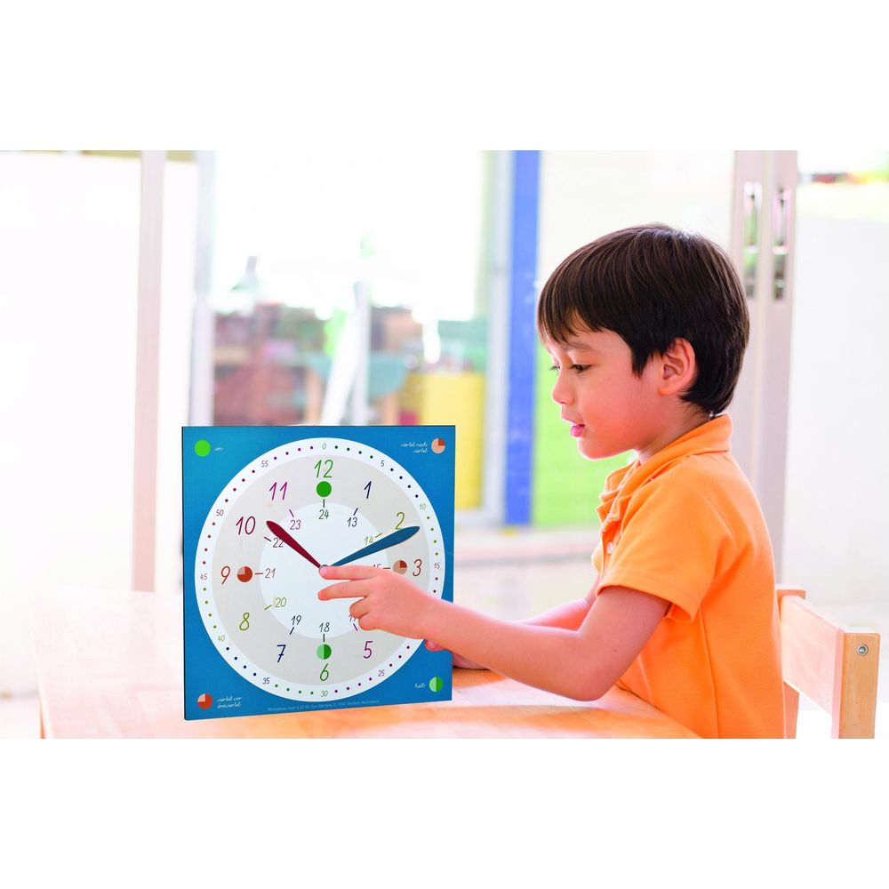 Un ragazzo in camicia arancione impara con un orologio colorato.