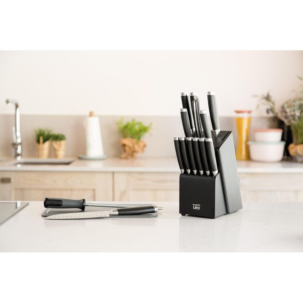 A knife block with several knives and a sharpening steel on a kitchen counter.