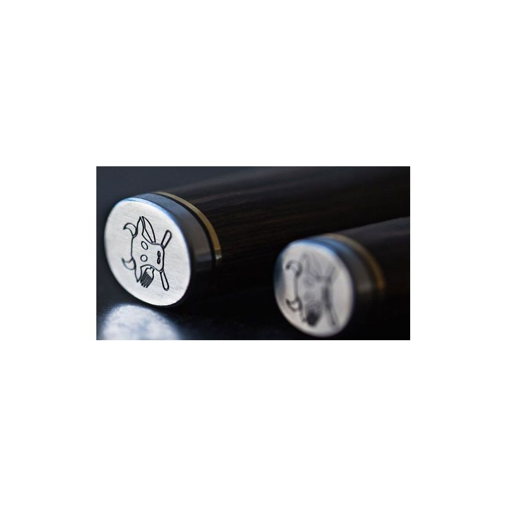 Zbliżenie na dwa ciemne drewniane uchwyty ze srebrnymi zaślepkami z grawerunkiem kozła.