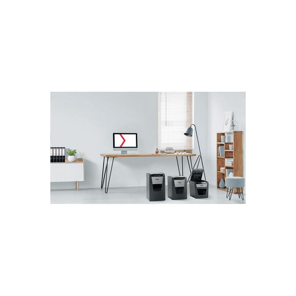 Ambiente d'ufficio con scrivania, monitor del computer, schedario e tre distruggidocumenti.