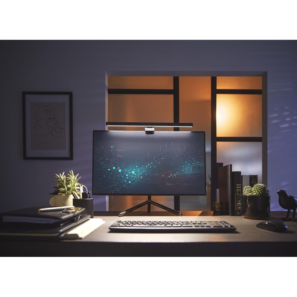 Una scrivania con monitor che mostra dati, tastiera, mouse, quaderni e piante.