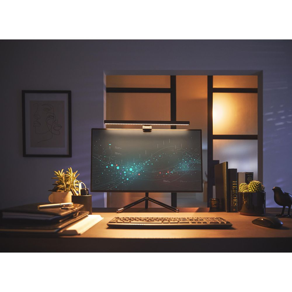 Un monitor del computer mostra dati. Tastiera, mouse, libri, piante e arte sulla scrivania.