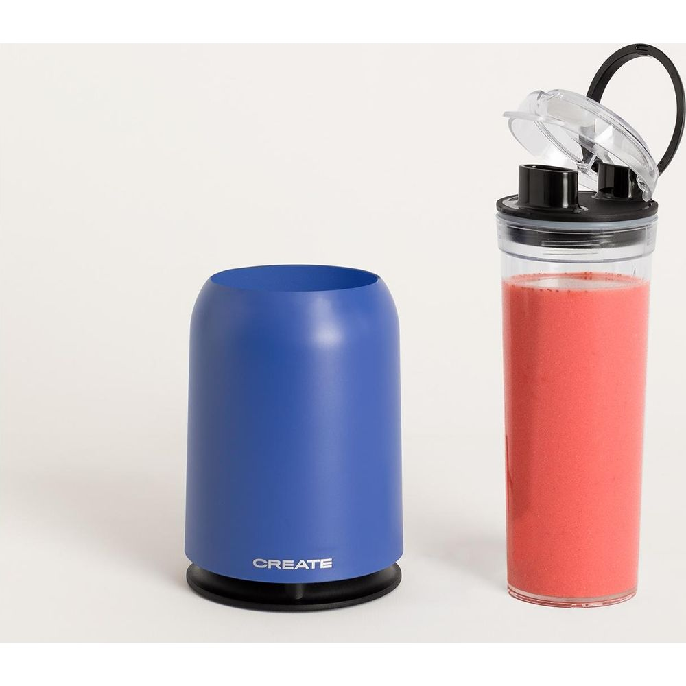 Un recipiente azul y un vaso con batido rojo se alzan uno al lado del otro.