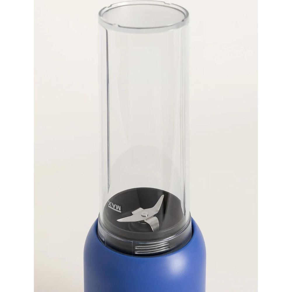 Primer plano de una licuadora portátil azul con recipiente transparente y cuchillas.