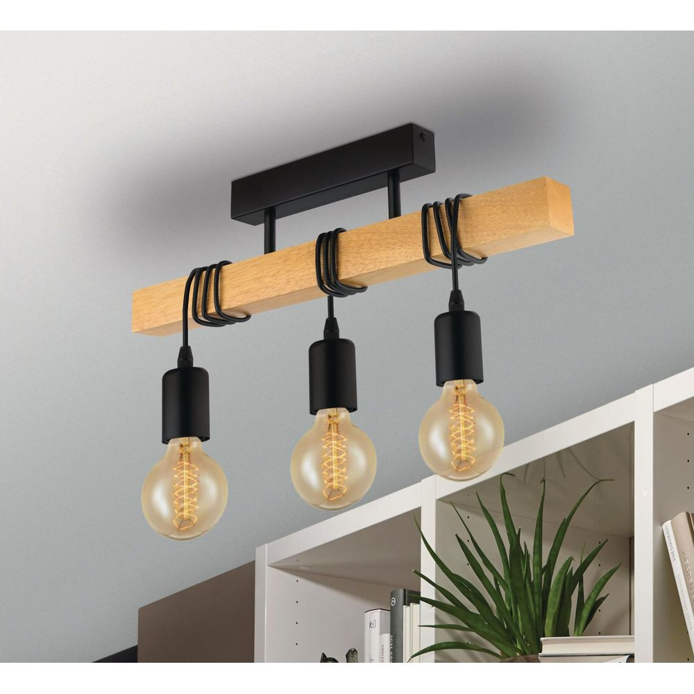 Une lampe avec une poutre en bois, trois douilles noires et des ampoules.