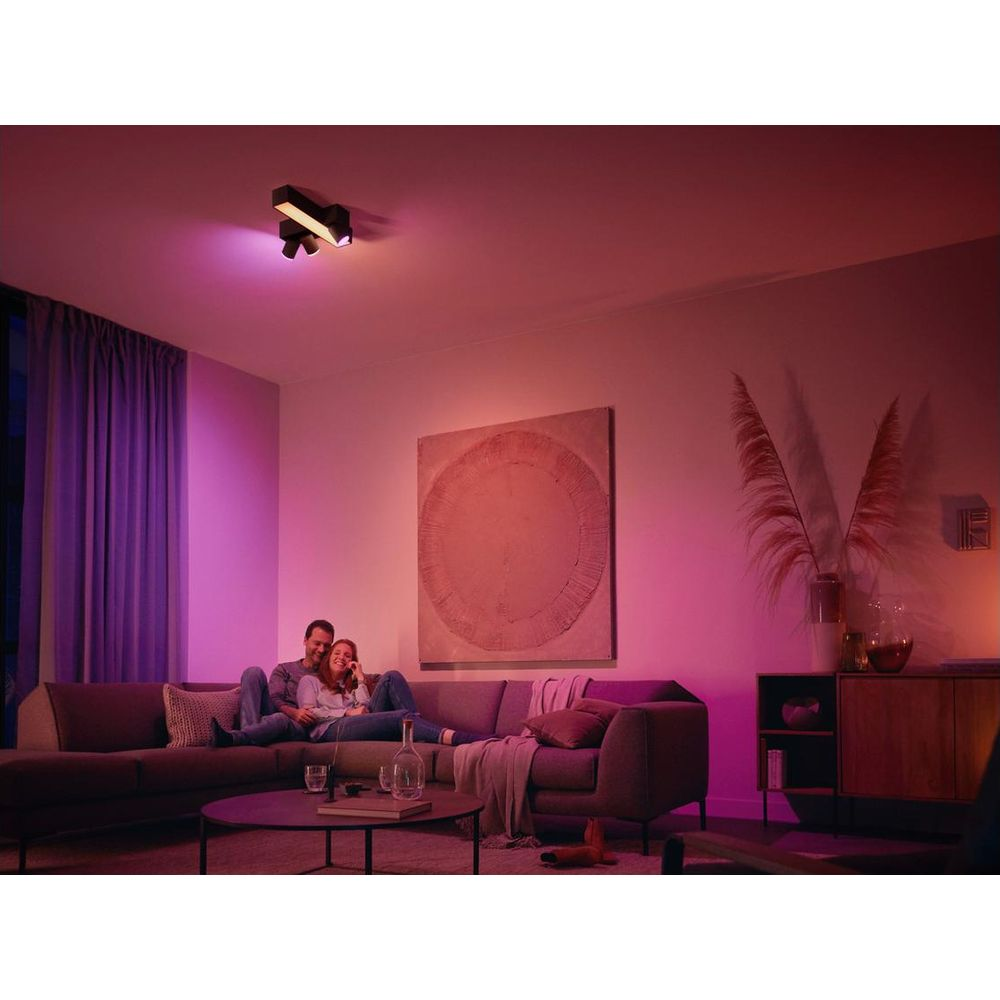 Een stel ontspant op een bank in een kamer met paarse verlichting.