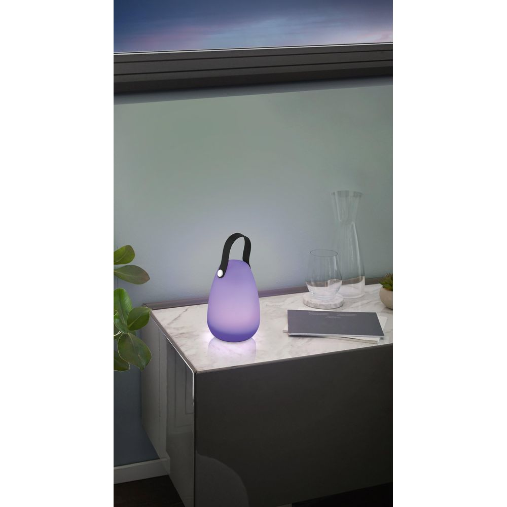 Lanterna viola con manico nero su tavolo di marmo vicino a bicchieri.