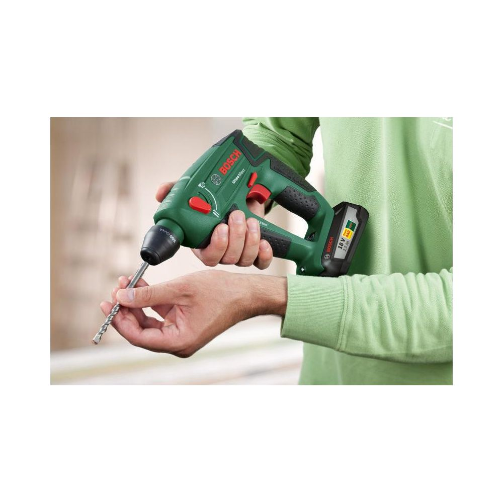 Osoba trzyma zielony młot udarowo-obrotowy Bosch z wiertłem.