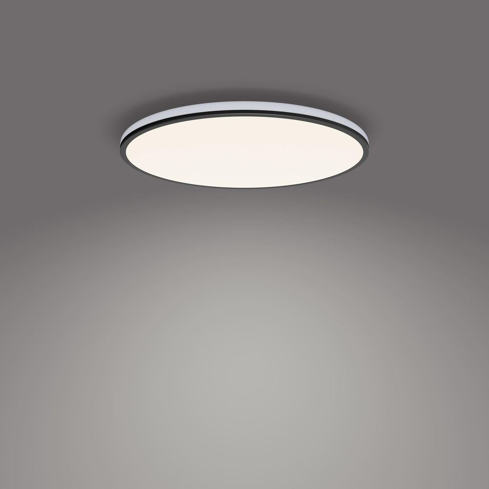 Un plafonnier moderne et rond avec cadre noir et éclairage blanc.