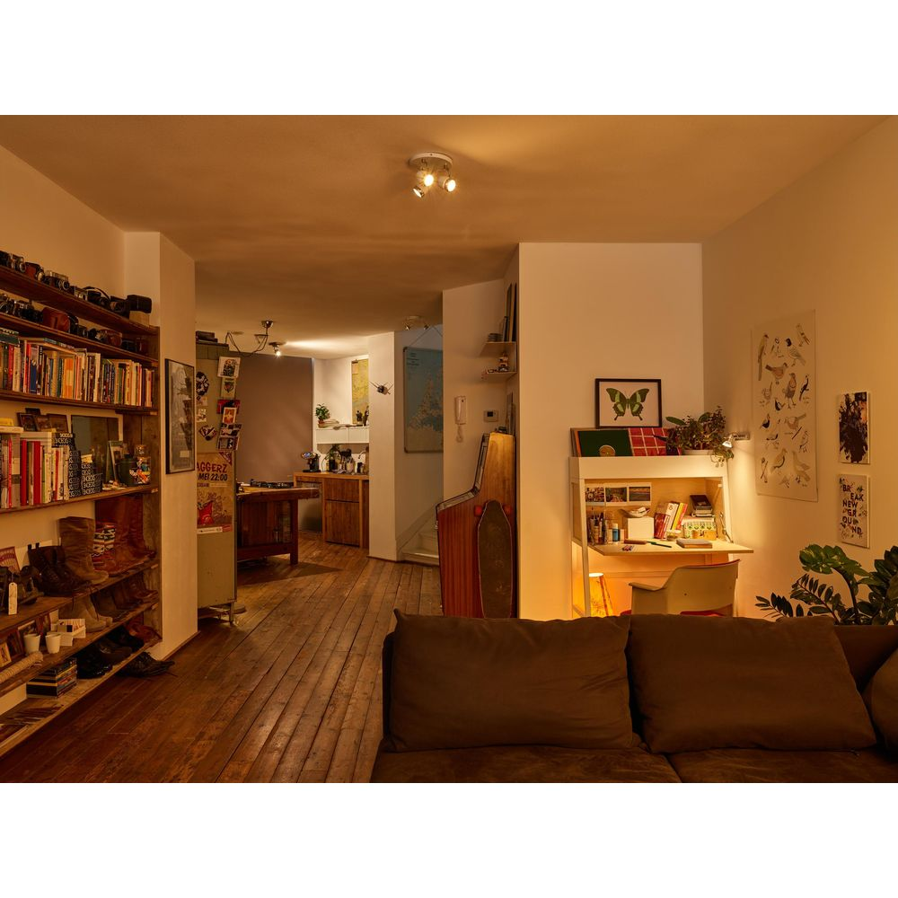 Un salon avec étagère, bureau, canapé et borne d'arcade.