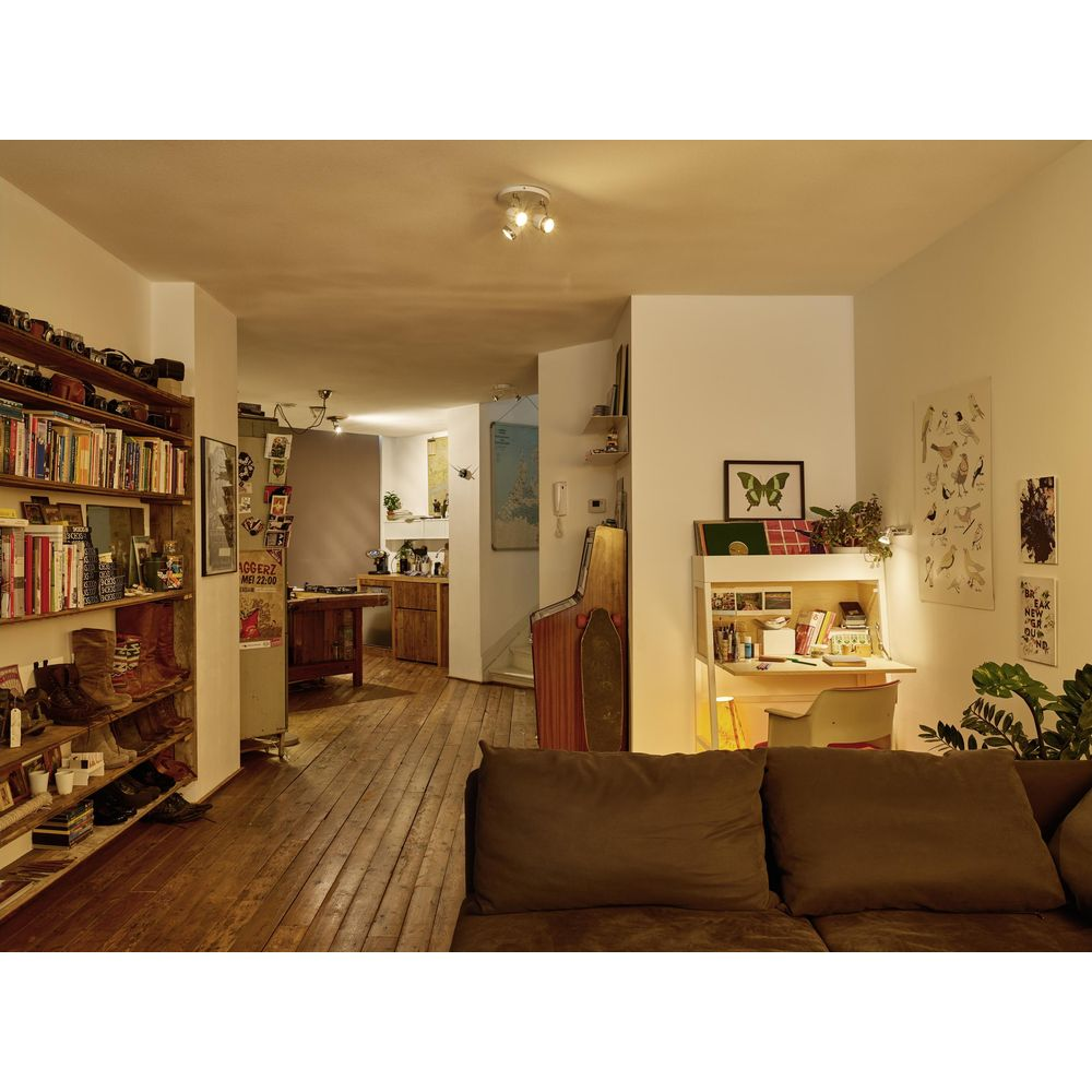 A living room with a wooden floor, bookshelf, desk, sofa, and retro arcade machine.