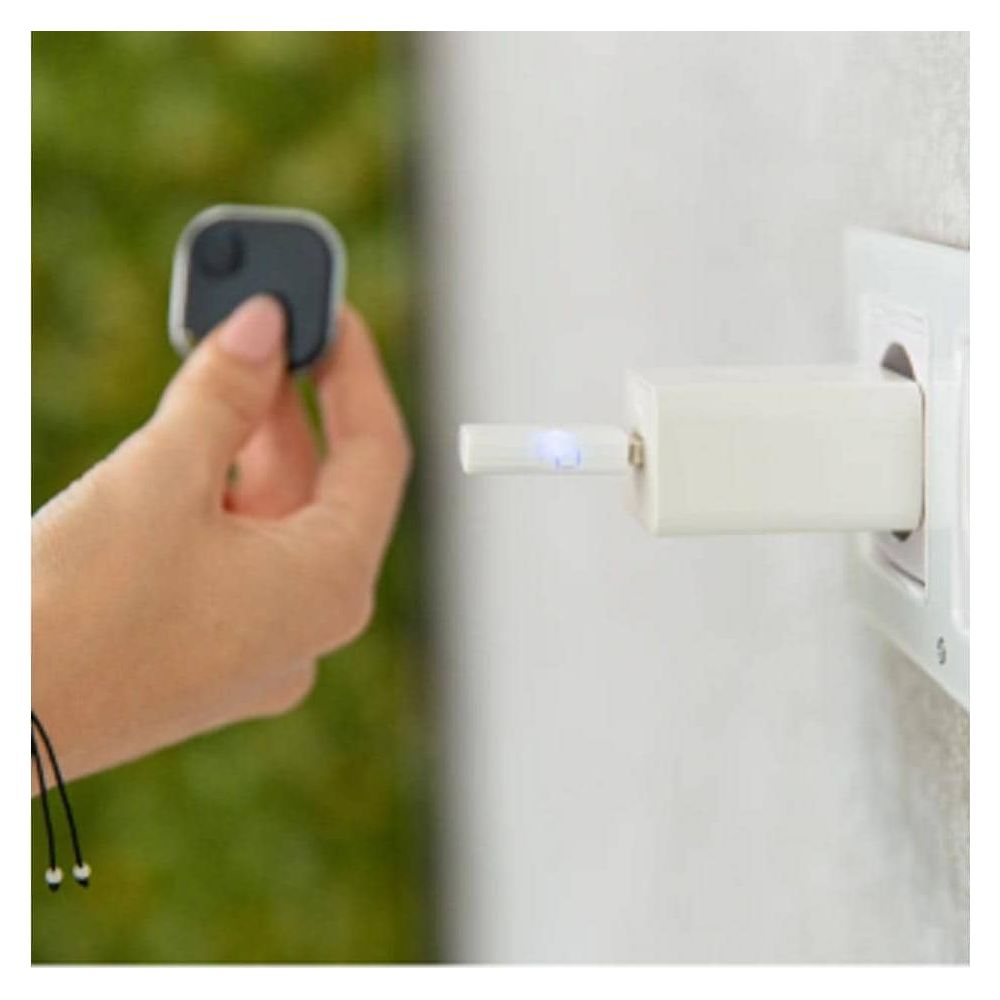 Une main tient un petit traqueur noir branché sur un chargeur.