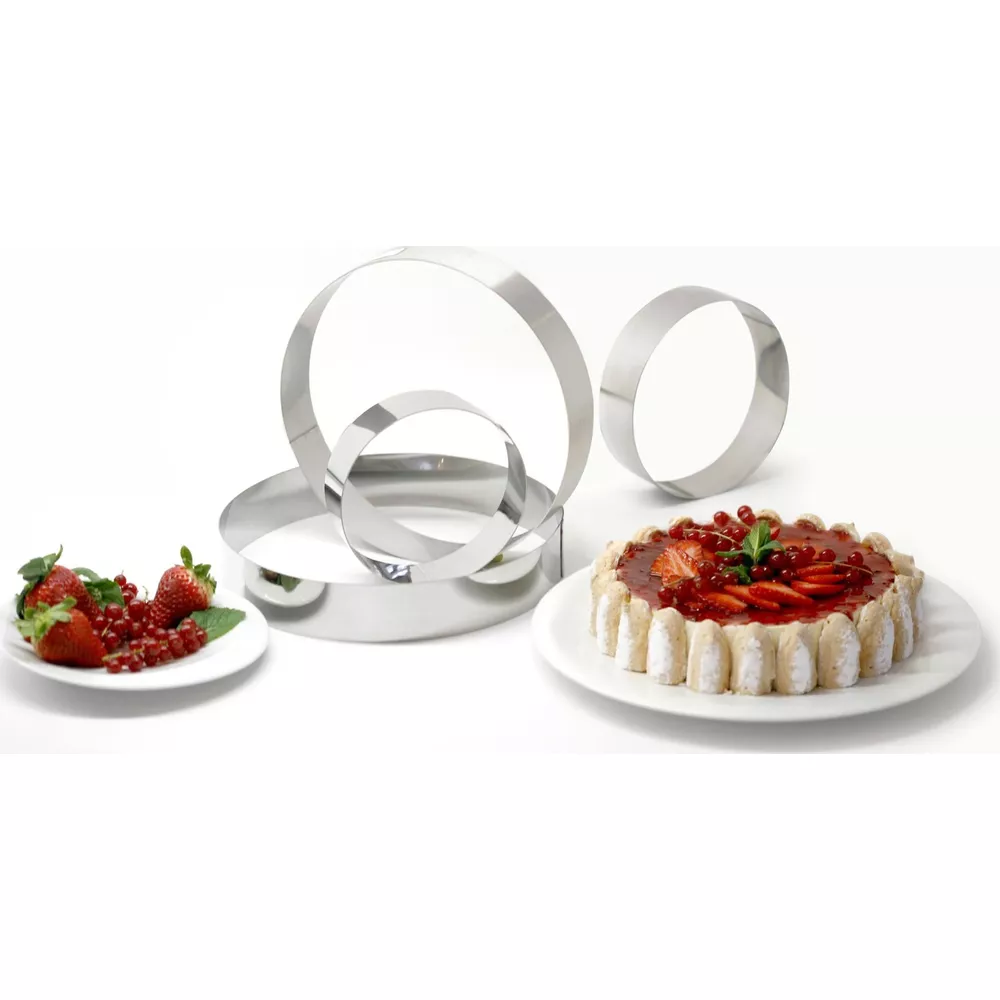 Kuchen mit Beeren und Metallringen auf weißem Hintergrund.