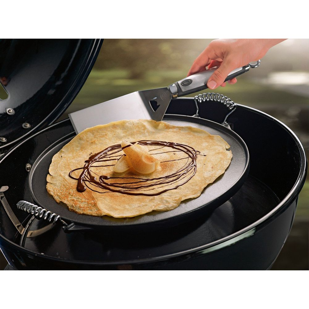 Ein Pfannkuchen mit Schokoladensoße und Birnenstücken auf einem Grill.