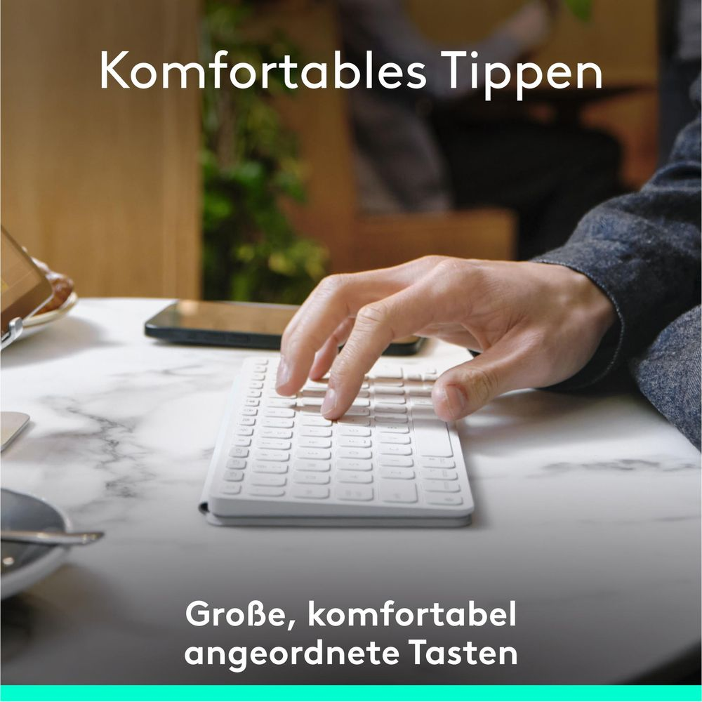 Eine Hand tippt auf einer weißen Tastatur mit großen, gut angeordneten Tasten.
