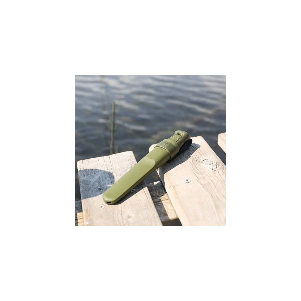 Grünes Messer mit Scheide liegt auf Holzplanken am Wasser.