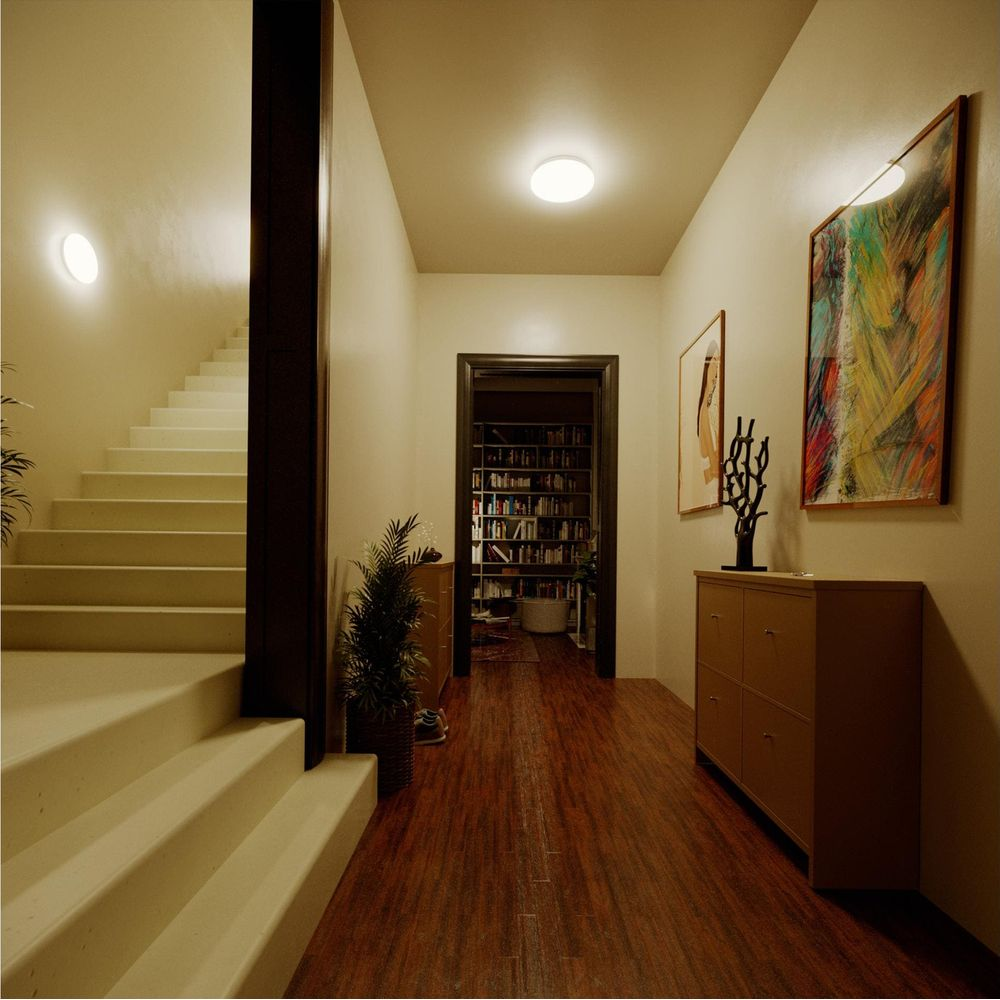 Corridoio con scale a sinistra, porta aperta su libreria e arte al muro.