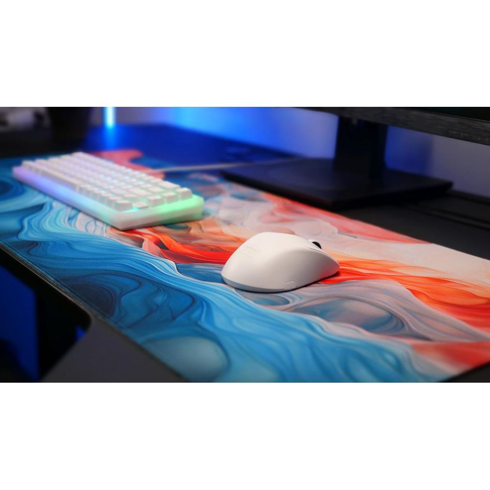 Un clavier et une souris blancs sur un tapis de bureau à motifs tourbillonnants bleus et rouges.