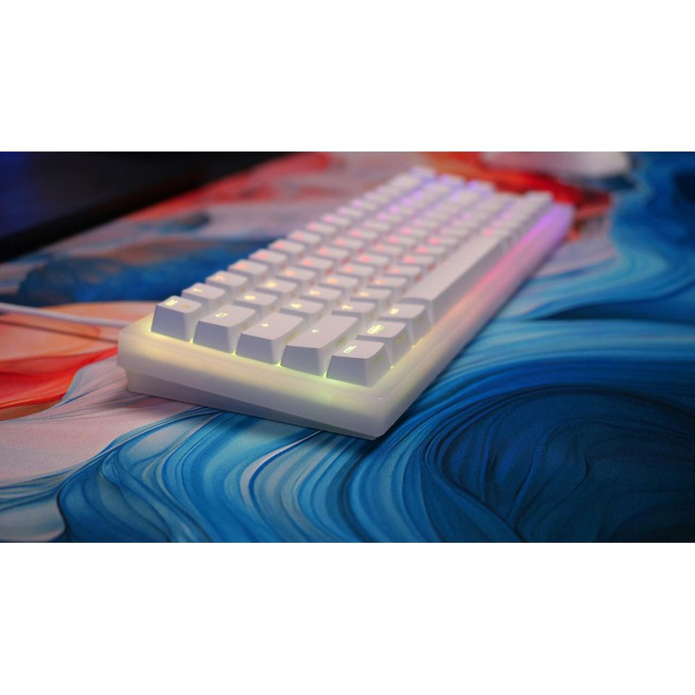 Un clavier blanc avec éclairage RVB repose sur un tapis de souris en marbre bleu et rouge.
