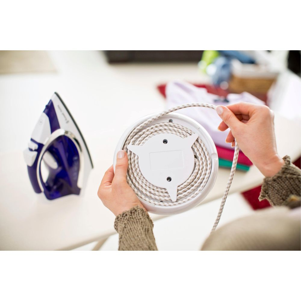 Osoba nawija sznurek na białą szpulę, obok leży żelazko.