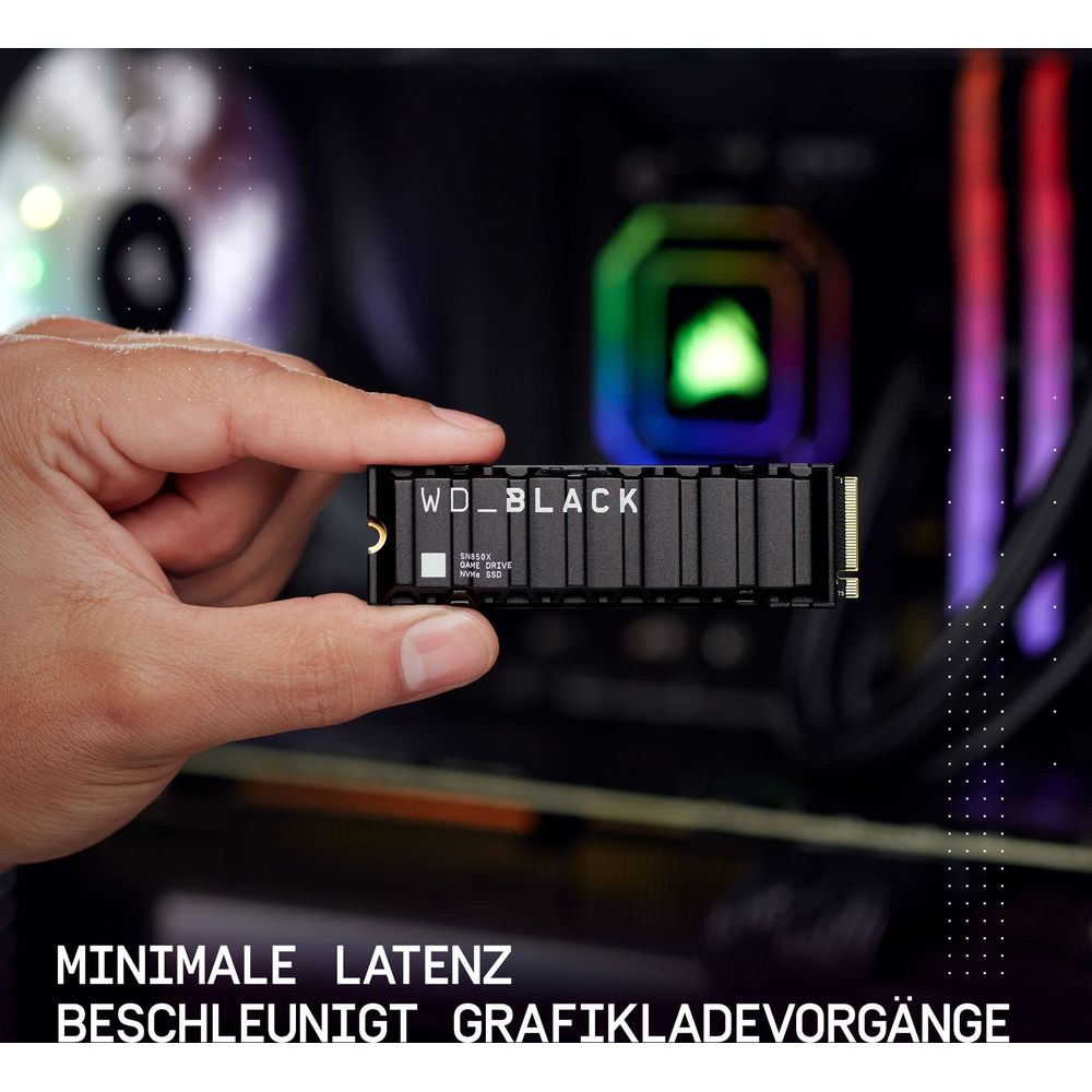 Ręka trzyma czarny dysk SSD WD_BLACK z radiatorem przed podświetlanymi elementami PC.