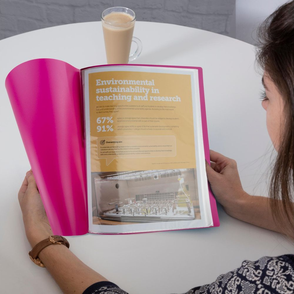 Kobieta czyta książkę o zrównoważonym rozwoju środowiska ze statystykami.