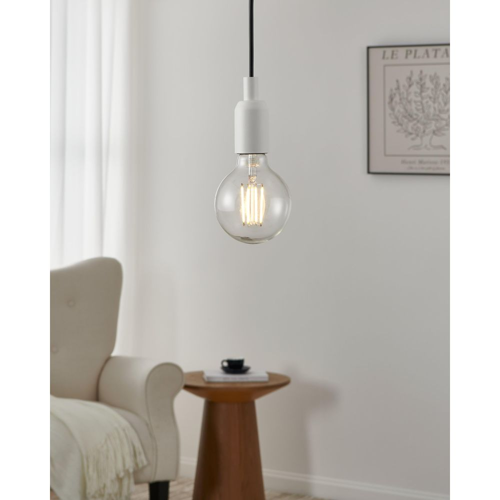 Une suspension avec une ampoule à filament est suspendue au-dessus d'une table en bois.