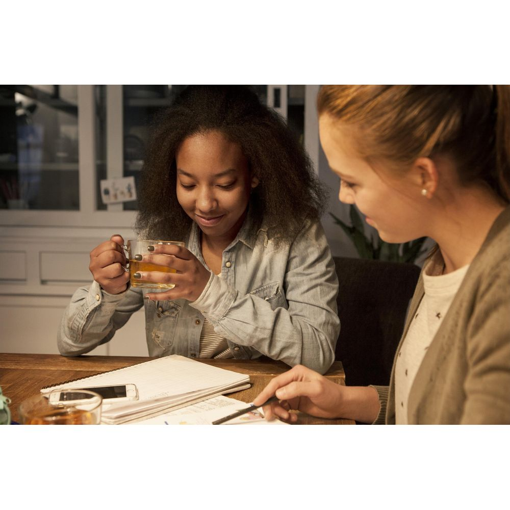 Deux filles étudient ensemble. L'une boit du thé, l'autre pointe des notes.