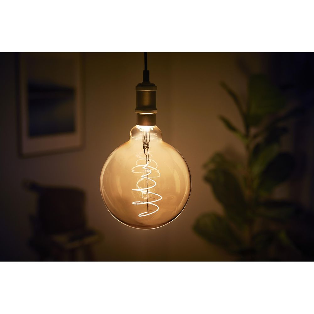 Een verlichte Edisonlamp met spiraalfilament, scherp met wazige achtergrond.