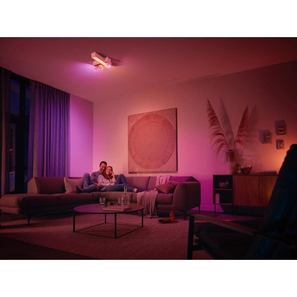 Een stel ontspant op een bank in een gezellige woonkamer, verlicht door gekleurde lampen.