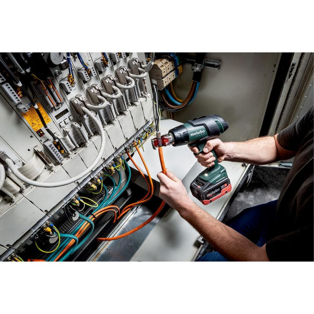 Osoba używająca bezprzewodowej opalarki na panelu elektrycznym z wieloma przewodami.