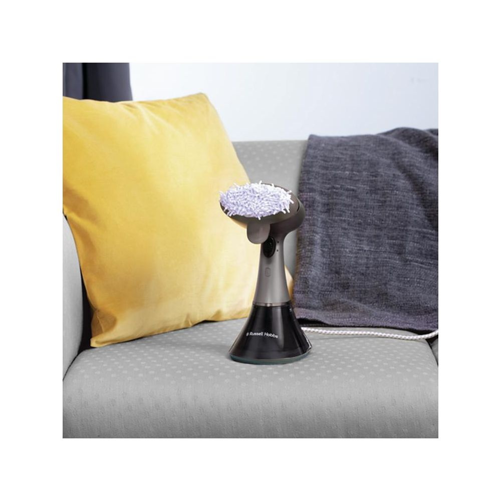 Ein Handdampfreiniger steht auf einem Sofa neben einem gelben Kissen.