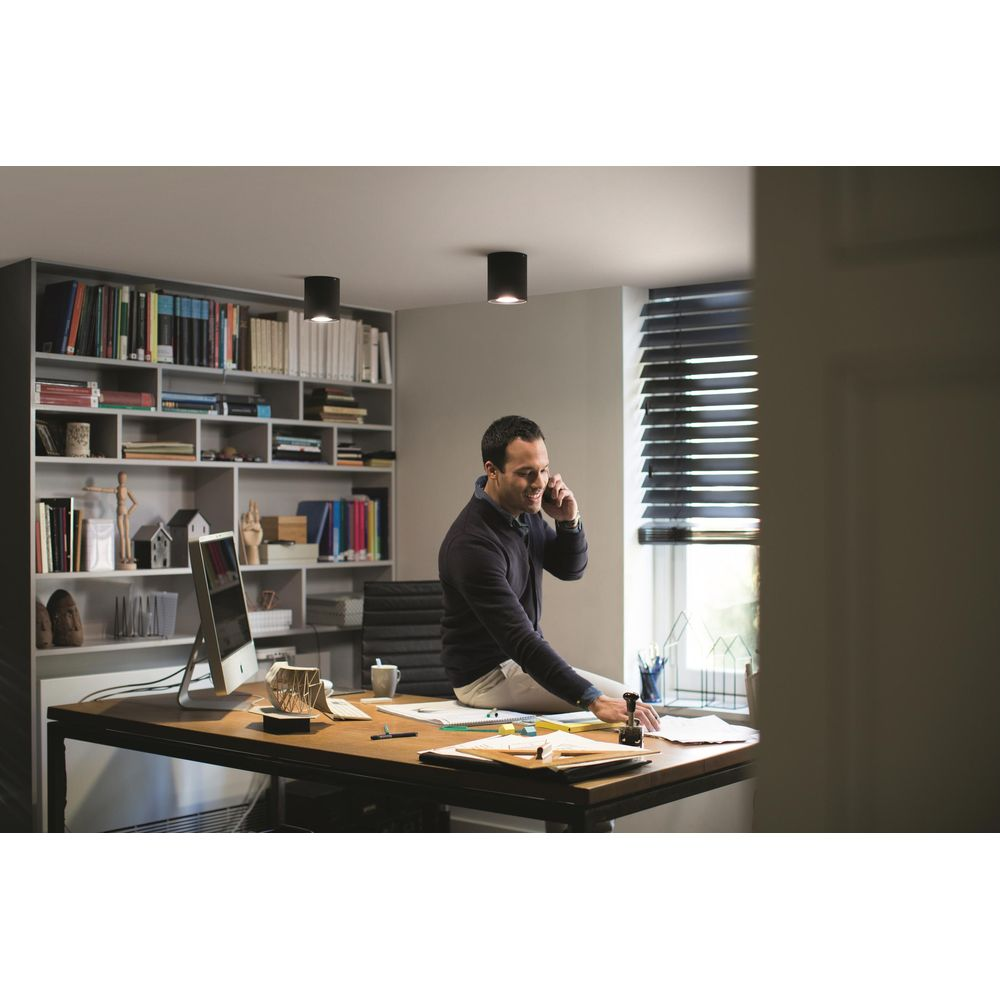 Mężczyzna w biurze rozmawia przez telefon, siedzi na biurku.