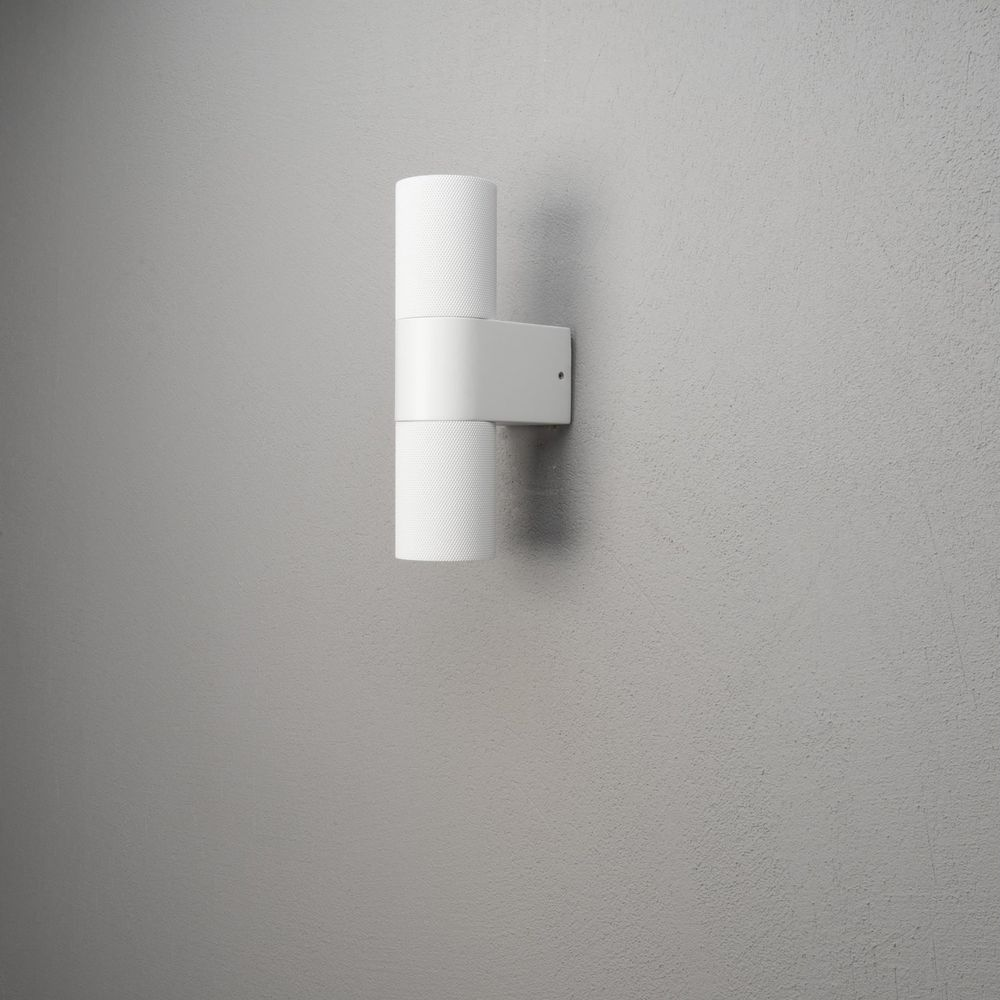 Eine weiße Wandleuchte mit zwei Zylindern an einer grauen Wand.