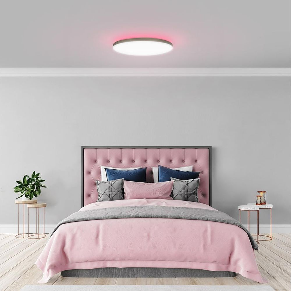 Ein Schlafzimmer mit einem rosa Bett, Kissen und einem Nachttisch.