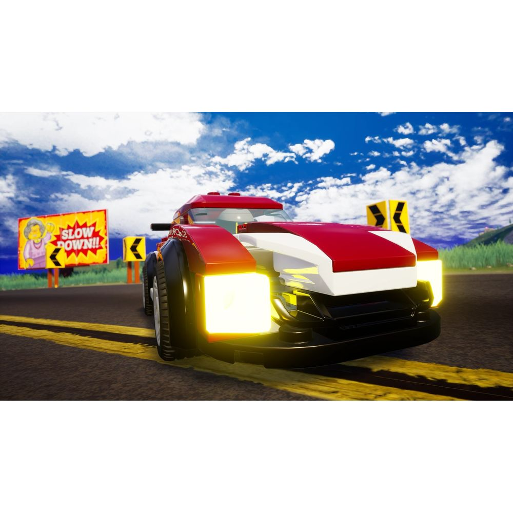 Une voiture de course Lego rouge et blanche roule sur une route avec un panneau "RALENTISSEZ".