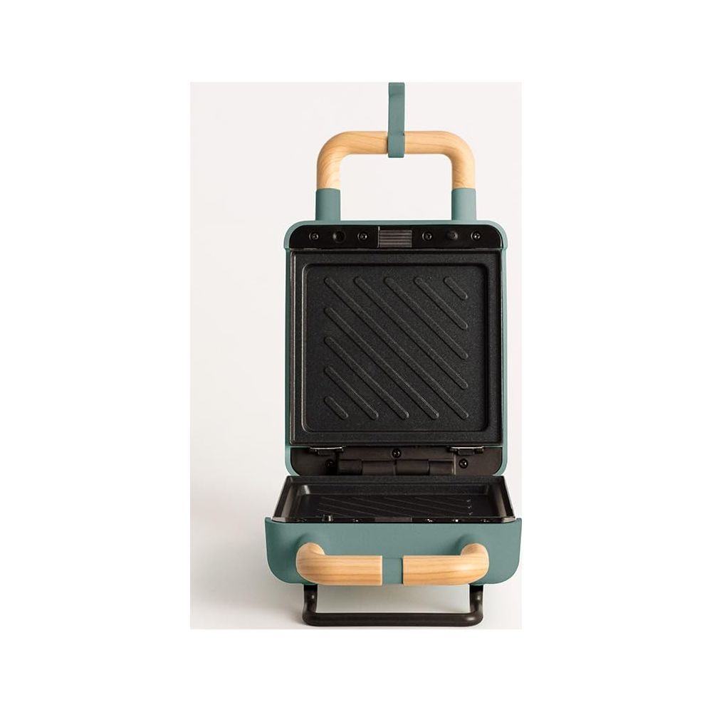 Sandwichera abierta color teal con asas de madera. Placa superior con líneas.