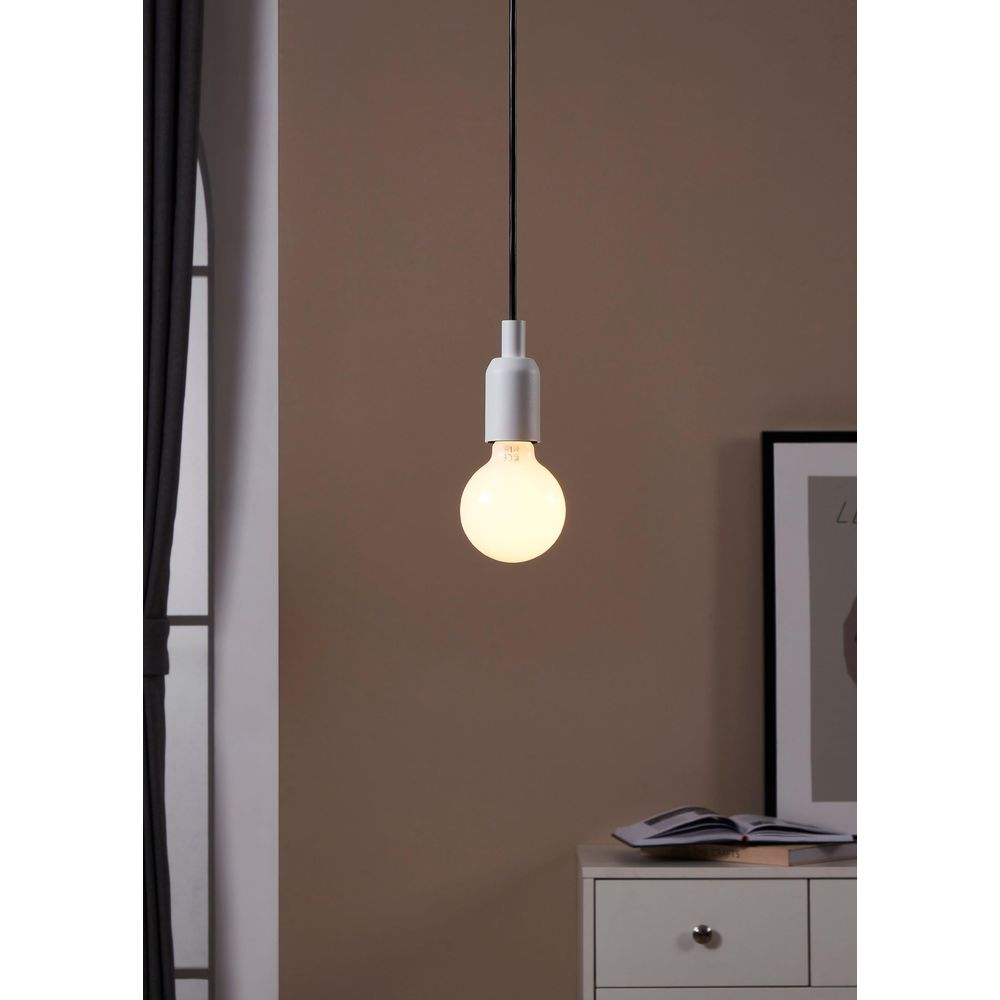 Una lampada a sospensione bianca con lampadina sopra un comodino.