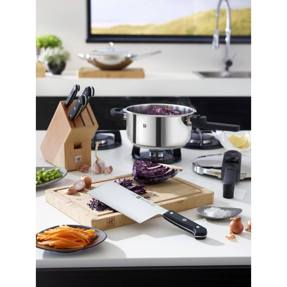 Garnek z czerwoną kapustą na kuchence, obok bloku na noże i warzyw.