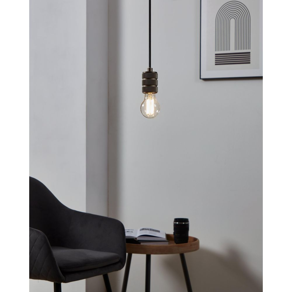 Une suspension avec une ampoule au-dessus d'une table d'appoint avec livre.