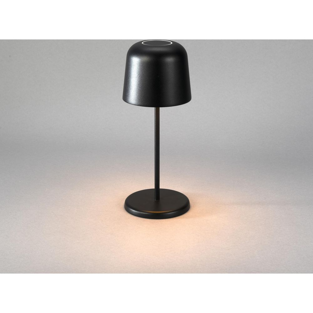 Eine schwarze Tischlampe steht auf einem grauen Hintergrund mit einem Lichtkreis um die Basis.